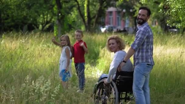 Rodzina z matką na krześle sheel spojrzeć wstecz i pomachać przed kamerą. — Wideo stockowe