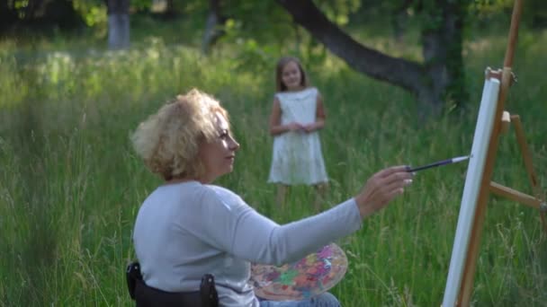 Kleines Mädchen posiert für Malermutter im Rollstuhl. — Stockvideo