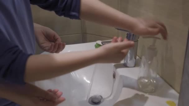 Młoda matka uczy syna higieny poprzez mycie rąk. — Wideo stockowe
