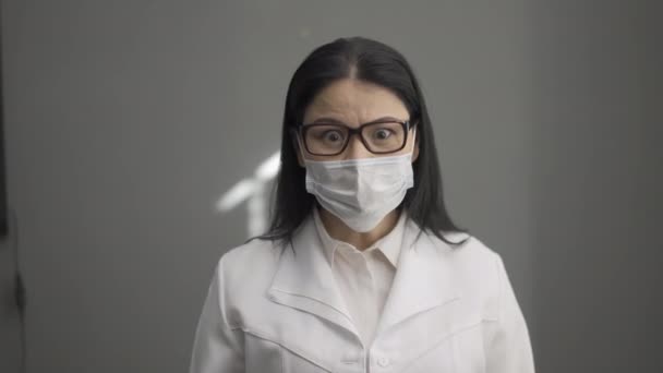Spuitende ontsmettingsmiddel arts kijkt bang voor de camera. — Stockvideo