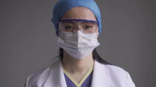 Asijský lékař při pohledu na kameru s brýlemi a maskou znečištění. — Stock video