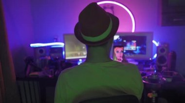 Blogcu genç adam sosyal medya için nargile içerken aynı zamanda neon ışıkları olan bir odada bilgisayarın önünde oturuyor. Karantina günlerinde uzakta ya da uzakta çalışan serbest çalışan ve evde dinlenen