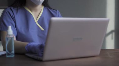 Bir hemşire laptopun arkasında çalışır, testleri kontrol eder ve hasta verilerini günceller. Coronavirus salgını sırasında yorgun kadın doktor. Yakın plan. Prores 422