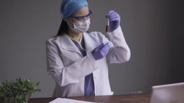 Mikrobiyolog doktor test tüplerinde Coronavirus ya da Cvid 19 'un kanında tıbbi üniforma giyerek test tüplerini inceliyor. Prores 422