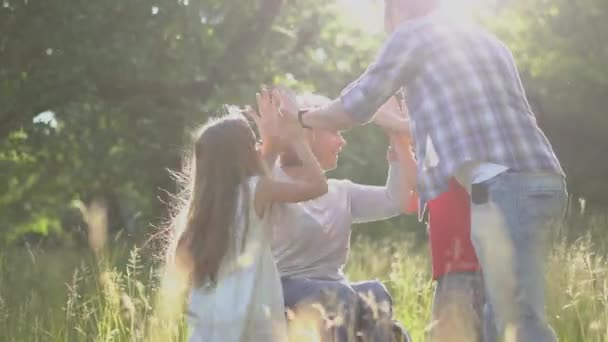 HI5 boldog gyermekek ad a szülők fogyatékkal élő anya egy kerekesszékben lóg a parkban vagy a természet kertjében. Gyümölcsfélék. — Stock videók