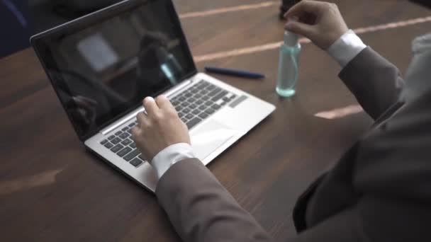 Egy lány üzleti ruhában egy irodában dolgozik egy laptopnak, fog egy kézi fertőtlenítőt és feldolgozza a kezét. Munka a koronavírus-pandémia karantén ideje alatt. Gyümölcsfélék — Stock videók