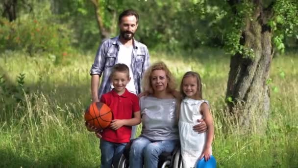 父、 2人の子供と車椅子の母親の愛する家族の家族の肖像画。子供連れのピクニックで家族。家族の概念。第四百二十二条 — ストック動画