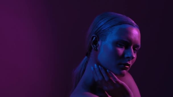 Schöne Blondine mit blauem Make-up steht unter Neonlicht — Stockvideo