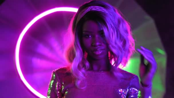 Sensuale donna afroamericana in posa sulla macchina fotografica in illuminazione al neon in un abito di paillettes d'argento. Prore 422 — Video Stock