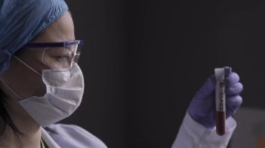 Doktor önünde üzerinde analiz için getirilen kan ya da biyomateryal olan bir test tüpü ya da koronavirüs testi aldı. Sağlık hizmeti konsepti. Prores 422