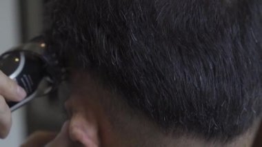 Kuaför genç bir adamın saçını kesiyor. Genç bir adamın kafasına yakın plan, kuaför kulağının üstünden saç kesiyor. Prores 422