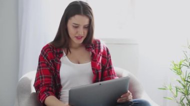 Kampüsteki kanepede elinde dizüstü bilgisayarla oturan ve video aracılığıyla ailesiyle ya da arkadaşlarıyla konuşan kırmızı tişörtlü kız. Prores 422