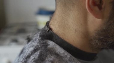 Saçları, karantina koronavirüsünü gevşetip saçını kestirmeye gelen genç bir adamın omuzlarına dökülüyor. Müşterinin omuzlarına odaklan. Prores 422