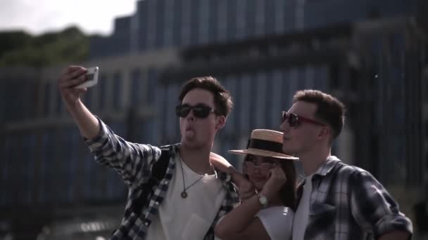 Turistas amigos tirar uma selfie no fundo da cidade. Os jovens se divertem viajando na capital do país juntos tirando fotos tirando fotos contra o pano de fundo das atrações. Prores 422 — Vídeo de Stock