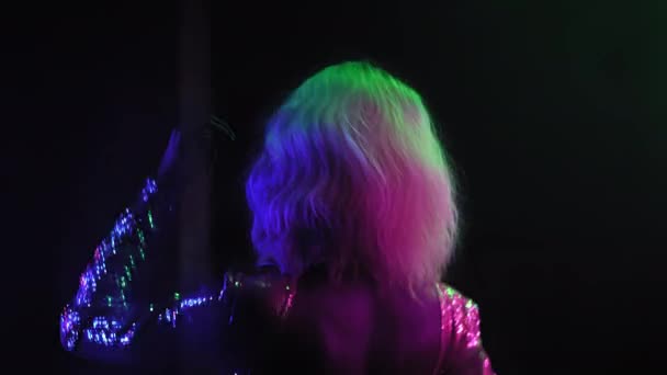 Achteraanzicht Afro-Amerikaans dansen in een donkere kamer met neonverlichting. meisje met blond haar dansend in een club geniet van muziek. Neon concept. Prores 422 — Stockvideo