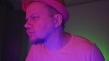 Bir adam, neon ışıklı odada otururken nargile içiyor ve en sevdiği müziği dinliyor. Neon konsepti. Prores 422