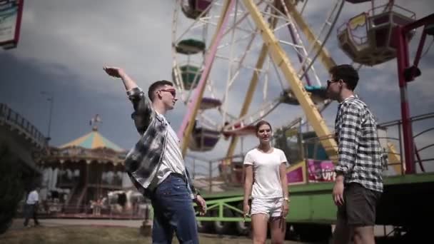 Przyjaciele hi five on a Ferris wheel background have fun travelling around the cities of the country together. Dwóch facetów i dziewczyna spotkali się w centrum. Koncepcja podróży. Prores 422 — Wideo stockowe