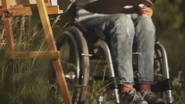 Malerin im Rollstuhl malt ein Bild von der Natur in einem Park oder Obstgarten. Kunsttherapiekonzept. Gesundheitskonzept. Menschen Lifestyle-Konzept. Goldfrau-Konzept. Prores 422 — Stockvideo