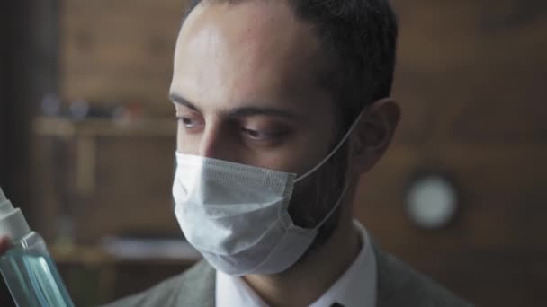 Ελεύθερος επαγγελματίας με προστατευτική μάσκα που δείχνει απολυμαντικό χεριών να στέκεται στο σύγχρονο γραφείο. Όμορφος άντρας προστατεύει τα χέρια του χρησιμοποιώντας απολυμαντικό. Σχέδιο εργασίας καραντίνας. Πρότυπα 422 — Αρχείο Βίντεο