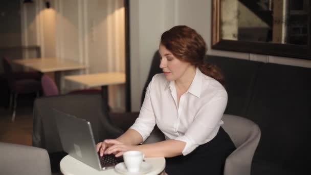 Zakenvrouw werkt op een laptop zittend in een fauteuil met een kop koffie op tafel. Mooie zakenvrouw bereidt een nieuw project maken concept op de computer. Vrouw in het zakenconcept. Prores 422 — Stockvideo