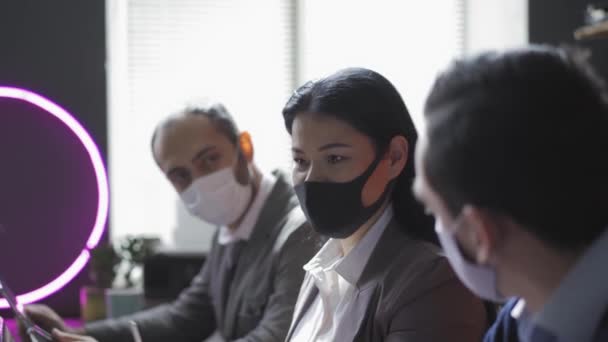 Tres autónomos con máscaras protectoras están sentados en la oficina trabajando en un nuevo proyecto durante la pandemia del coronavirus. Concepto de cuarentena. Prores 422 — Vídeo de stock