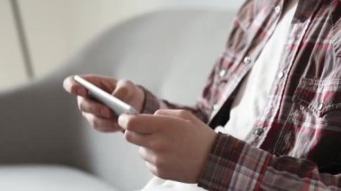 Genç adam akıllı telefonda oynuyor. Oturma odasında, kanepede oturuyor. Çalışmadan önce ya da sonra oyun oynarken akıllı telefonu erkeğin elinde kapat. Prores 422