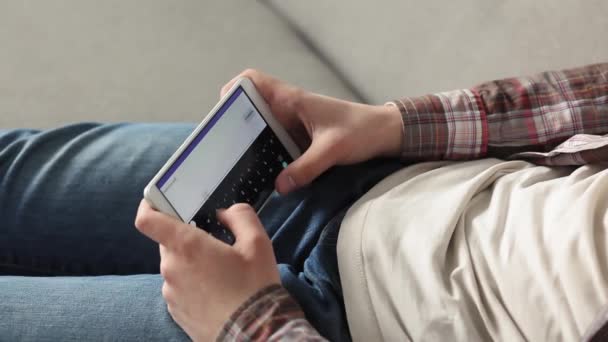 Estudante jogando jogos no smartphone deitado no sofá em uma sala de estar. Jovem a jogar antes ou depois dos estudos. Prores 422 — Vídeo de Stock