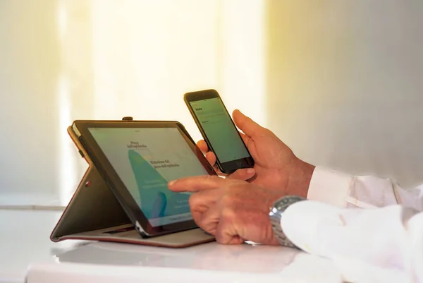 Tablet ve cep telefonu beyaz gömlekli bir adam tarafından tutuluyor - doktor ya da iş adamı internette veri analiz ederken.