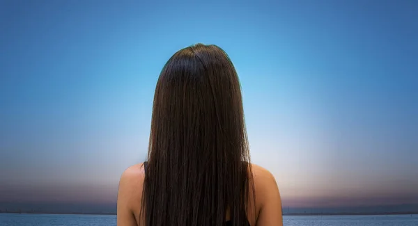 Kız gün batımını izlerken sırtüstü yatar - kahverengi saçlı ve açık tenli.