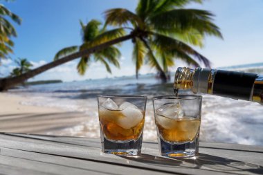 Karayip sahilinde iki kişilik içki. İki bardak içki kaygısız bir tatil konsepti için. Denize uzanmış avuç içleri için..
