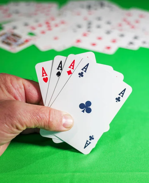 man plays cards on the green table - poker of aces in the player\'s hand