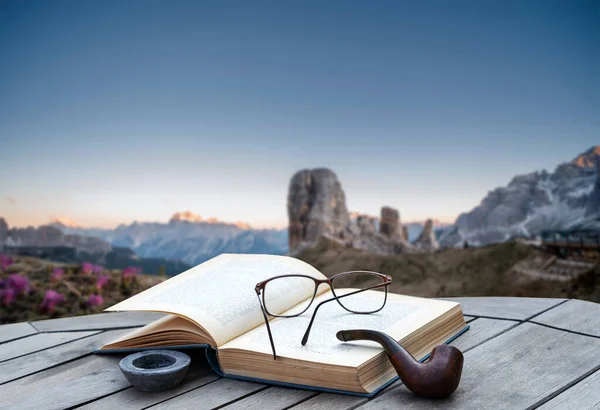 Kitap ve boru bir dağ manzarasının önünde - yüksek dağlarda tatil rahatlatma konsepti