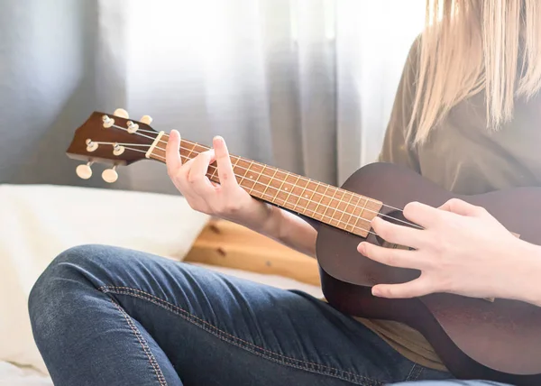 Yatak odasında telli çalgılarla müzik çalan bir kadın. Ukulele Çalıyor