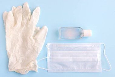 Tıbbi sağlık koruması. COVID-19 salgını. Tıbbi eldivenler, tıbbi koruyucu maske ve antiseptik mavi arka planda..