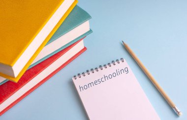 Okula dönelim. Kitaplar, bir kalem ve mavi arka planda 