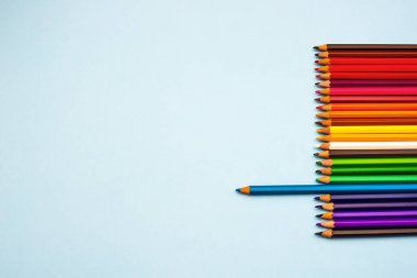 Mavi bir arkaplanda izole edilmiş renkli kalemler, kopyalama alanı. Okula geri dön.