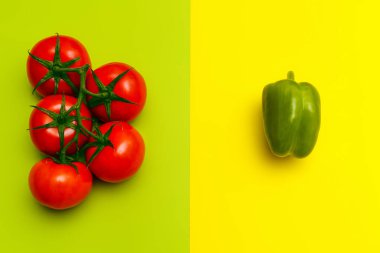 Geometrik sarı-yeşil arka planda olgun domates ve biberlerin düz bileşimi. Hasat ve vejetaryenlik kavramı. Kapatın. Uzayı kopyala Yeni eğilim