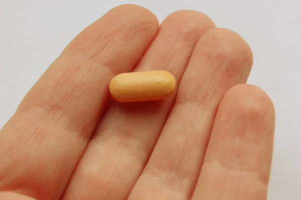 Hand holding the pill in the palm of the hand. Isolated on a white background. — Stock Photo, Image