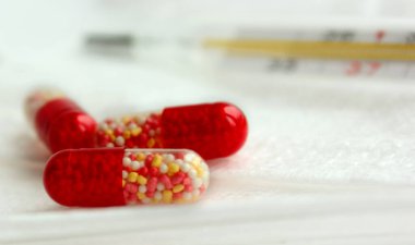 İlaçlar yakın mesafeden beyaz arka plana yerleştiriliyor. Paketlenmemiş kırmızı ve beyaz tabletler. Termometre yüksek ateşi gösteriyor. Arka plan bulanık. Merkür termometresi. Kapsama Alanı Pankartı