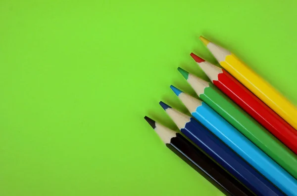 緑の背景に色鉛筆 6色黒 鉛筆はよく研がれている 平置きだ 隔離されてる アート アートセラピー レジャー 鉛筆は右下隅に配置されます — ストック写真