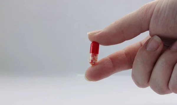 Parmak Işaret Parmağı Arasında Tableti Tutan Tablet Kırmızı Beyaz Laçlar — Stok fotoğraf