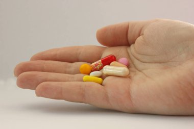 Farklı renk ve şekillerden oluşan tabletler avucunuzun içinde duruyor. Bütünün avuç içi. Kırmızı, beyaz, sarı, pembe tabletler. Sol tarafta yer alıyor. Uyuşturucu alıyordum. Tedavi için. Evde ilk yardım çantası