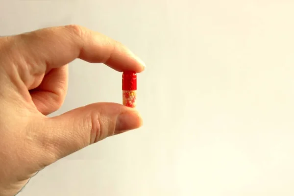 Mano Sosteniendo Tableta Entre Pulgar Índice Cápsula Blanca Roja Mano — Foto de Stock