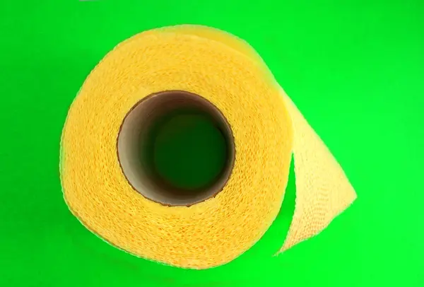 Basit tuvalet kağıdı yeşil arka planda sarıdır. Hijyen. İzole et. Tuvalet kağıdı rulosu yeni. WS. Yukarıdan görüntüle — Stok fotoğraf