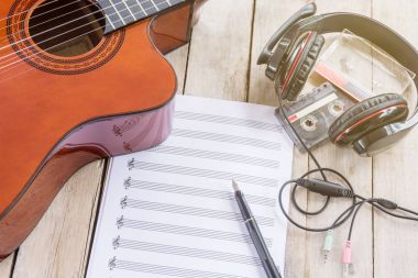 Akustik gitar, notalar, büyük kulaklık, dolma kalem, teyp kaseti ahşap tablo