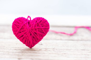 Kırmızı vintage bokeh yumuşak ışık arka plan ile ahşap üzerinde kalp şeklinde yün örgü