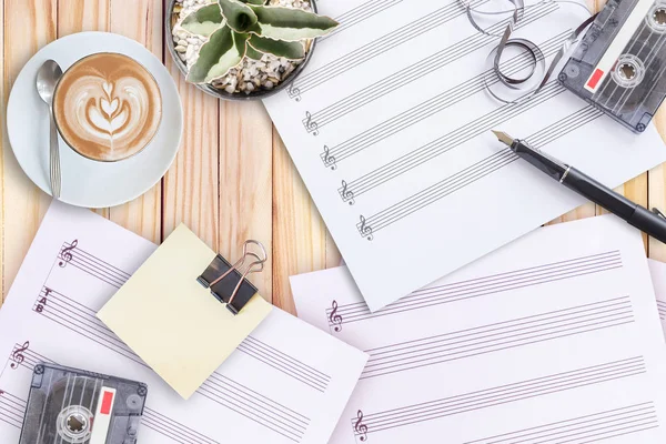 Notblad, kaktus, reservoarpenna, tapekassett och kaffe latte på träbord — Stockfoto