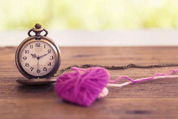 Collar reloj de bolsillo de estilo antiguo con corazón de lana de punto en una superficie de madera —  Fotos de Stock