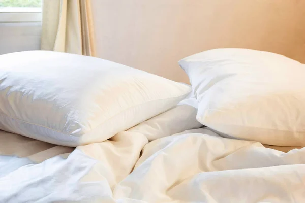 Almohada blanca y manta con arruga desordenada en la cama en el dormitorio con iluminación en la parte superior izquierda, de dormir en una larga noche de invierno . —  Fotos de Stock