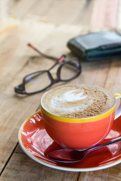 Orange kopp kaffe latte art med blad mönster på trä bakgrund, Stäng upp konst kaffe i morgon — Stockfoto